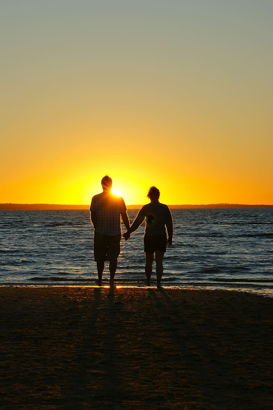 A couple holding hands on a sunset beach