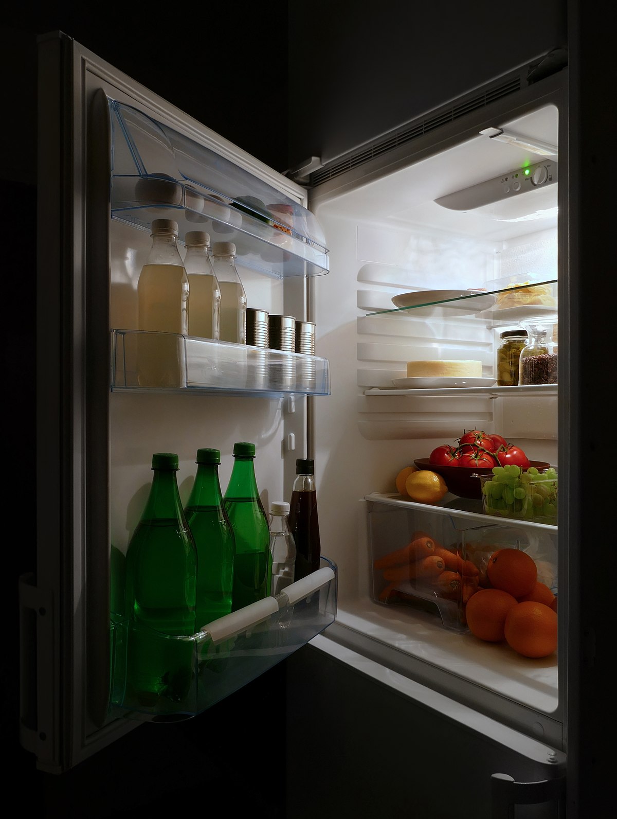 Person standing in front of an open fridge, looking at food options.