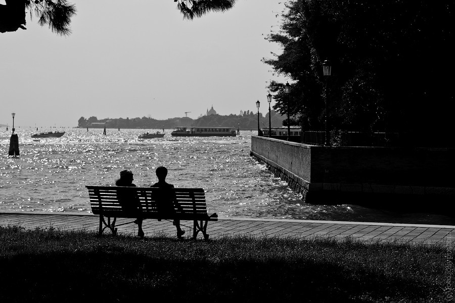 Two people sitting on a bench, looking in opposite directions